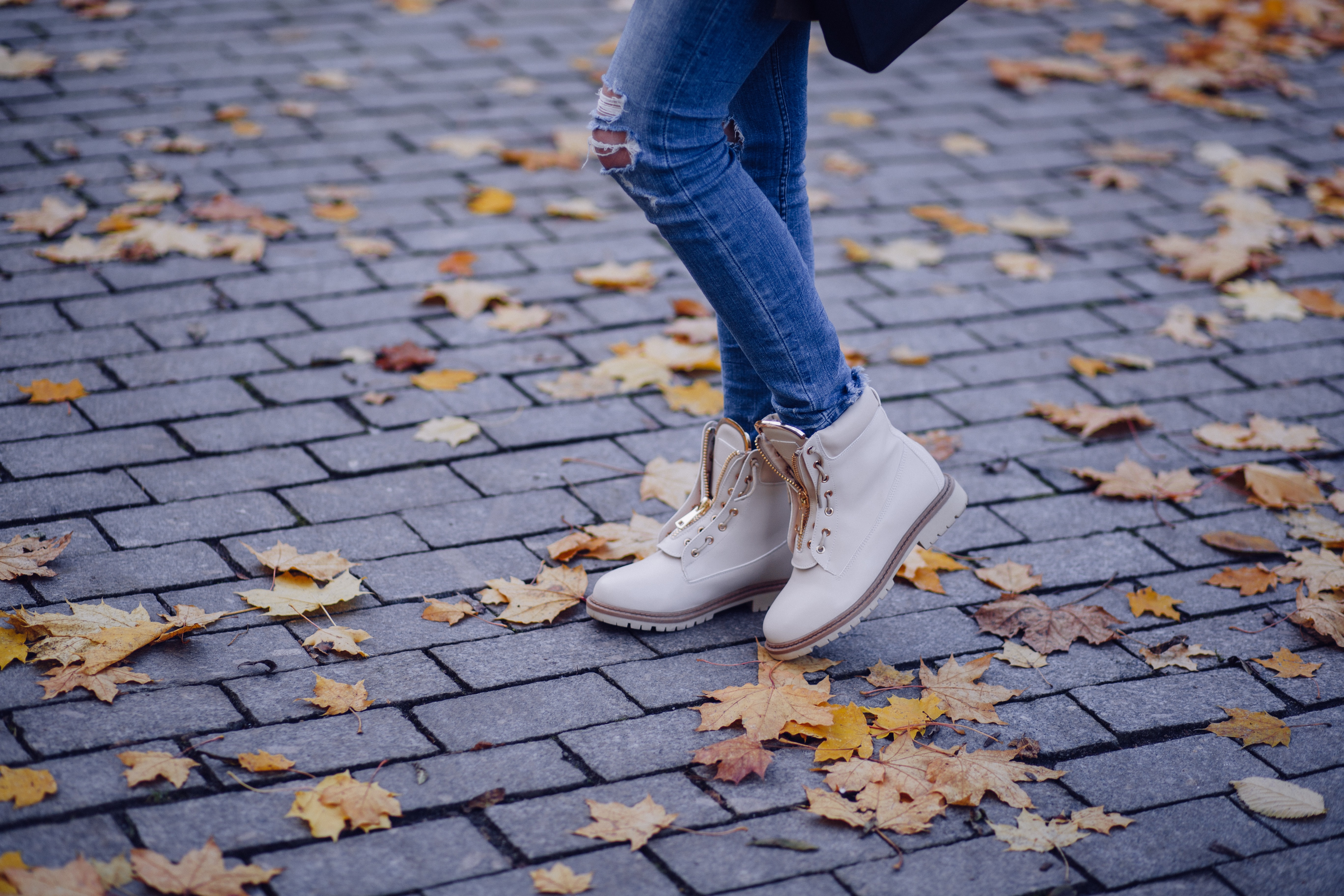 Woman's legs in jeans standing on brick walkway